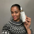 Woman holding a skincare product with a plain background