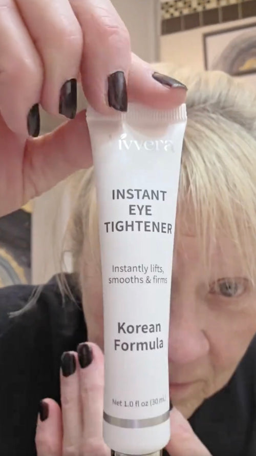 Hand holding a tube of 'Instant Eye Tightener' with a blurred background