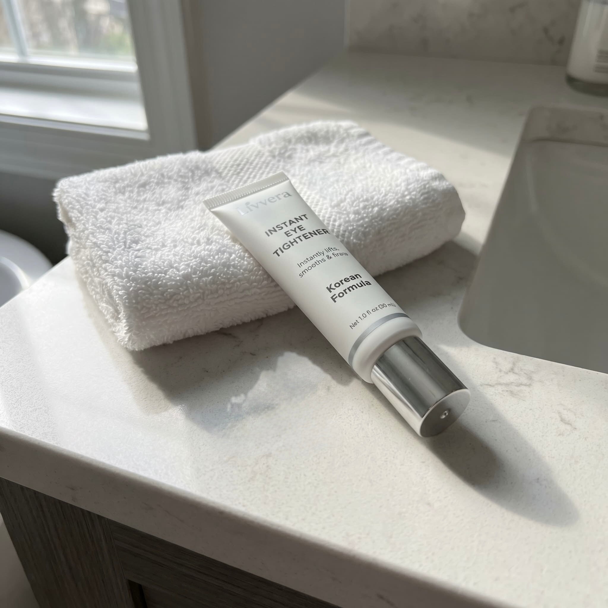 Skincare bottle on a marble surface with a towel in the background
