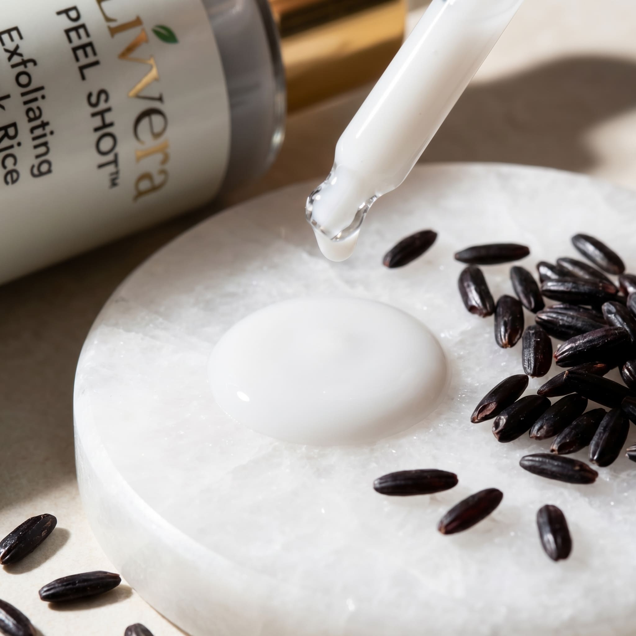 Exfoliating product being applied to skin with black rice seeds nearby, featuring the Livera brand.