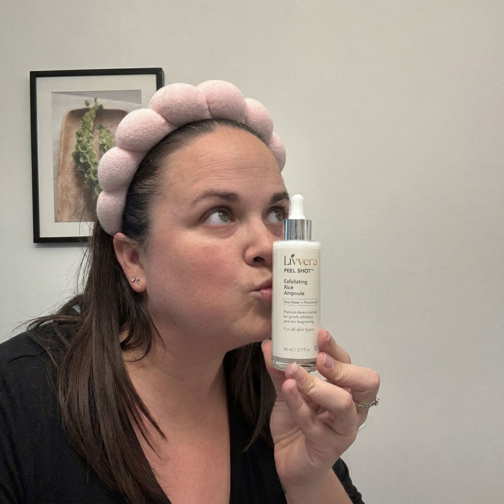 Woman holding a skincare bottle with a neutral background