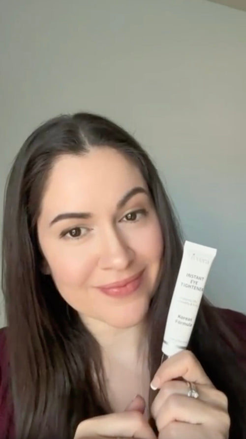 Woman holding a skincare product against a plain background